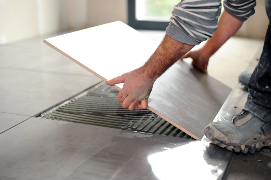 23874071 - man laying floor tiles